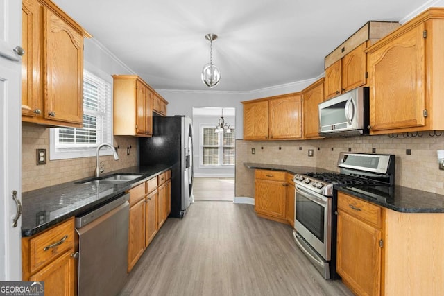 kitchen featuring appliances with stainless steel finishes, sink, light hardwood / wood-style flooring, an inviting chandelier, and hanging light fixtures