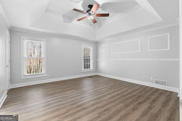 empty room with a raised ceiling, crown molding, and ceiling fan