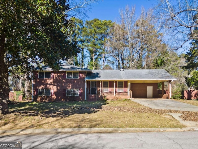 split level home featuring covered porch, a front yard, and a carport