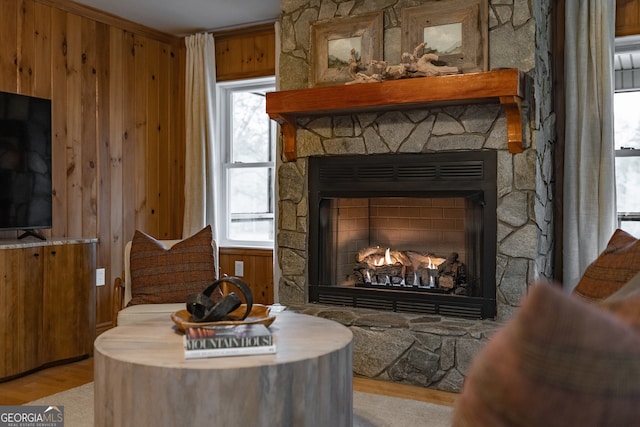 sitting room featuring wood walls, crown molding, a fireplace, and light hardwood / wood-style flooring