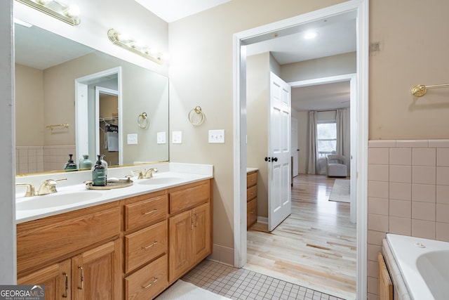 bathroom with tile patterned floors, a bathtub, vanity, and tile walls