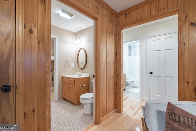 bathroom featuring wood walls, hardwood / wood-style floors, vanity, and toilet