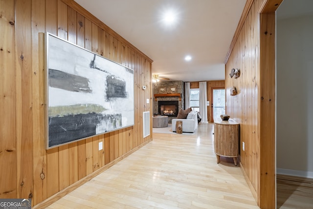 hall featuring light wood-type flooring and wooden walls