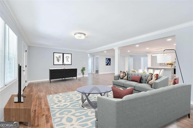 living room with plenty of natural light, ornamental molding, and decorative columns