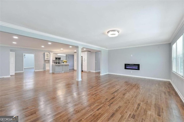 unfurnished living room with wood-type flooring and crown molding