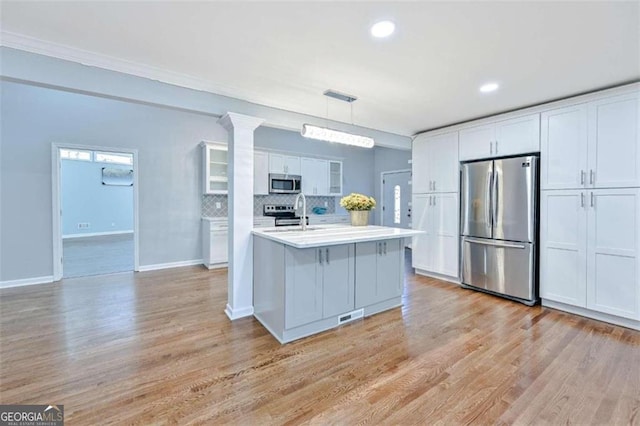 kitchen featuring appliances with stainless steel finishes, light wood-type flooring, white cabinetry, and pendant lighting