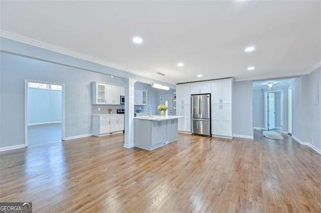 kitchen featuring backsplash, stainless steel appliances, sink, white cabinets, and a center island