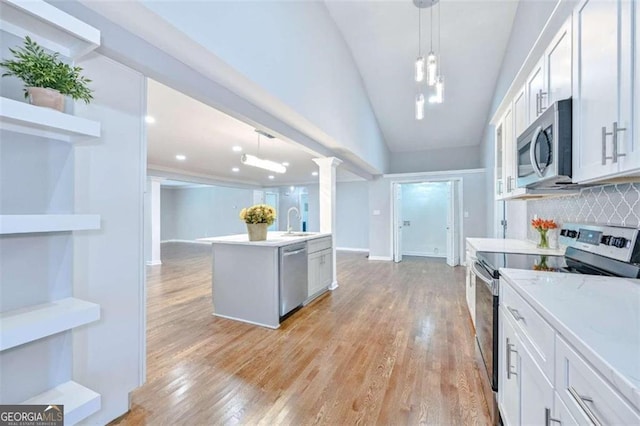 kitchen with sink, hanging light fixtures, appliances with stainless steel finishes, tasteful backsplash, and white cabinetry