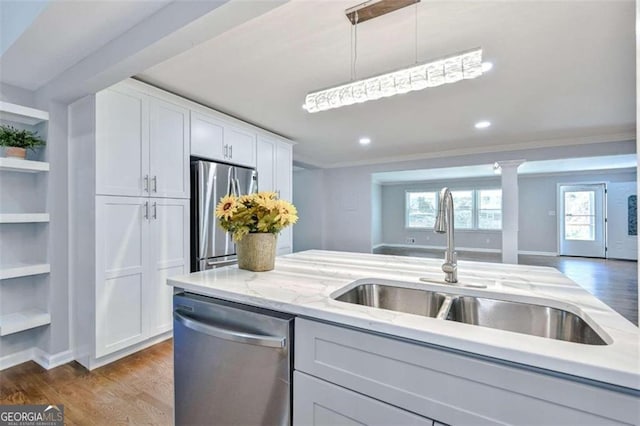 kitchen featuring sink, light stone counters, decorative light fixtures, white cabinets, and appliances with stainless steel finishes