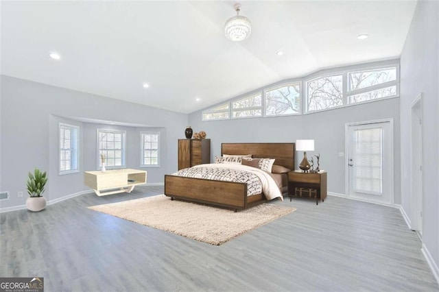 bedroom with light hardwood / wood-style floors, multiple windows, and lofted ceiling