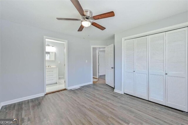 unfurnished bedroom with ceiling fan, a closet, light hardwood / wood-style flooring, and ensuite bath