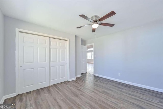 unfurnished bedroom with ceiling fan, wood-type flooring, and a closet