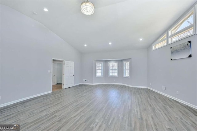 empty room with light wood-type flooring, vaulted ceiling, a healthy amount of sunlight, and a notable chandelier