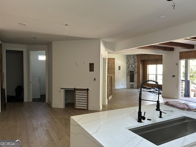 kitchen featuring beam ceiling, sink, and light hardwood / wood-style flooring