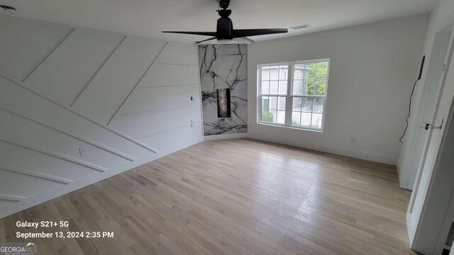 interior space featuring a large fireplace, ceiling fan, and light hardwood / wood-style floors