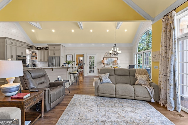 living room featuring dark wood-type flooring, vaulted ceiling with skylight, and an inviting chandelier