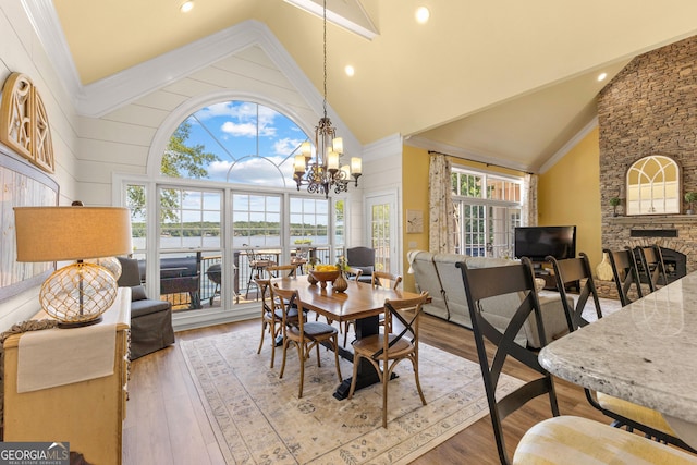 dining area with a fireplace, an inviting chandelier, hardwood / wood-style flooring, plenty of natural light, and high vaulted ceiling