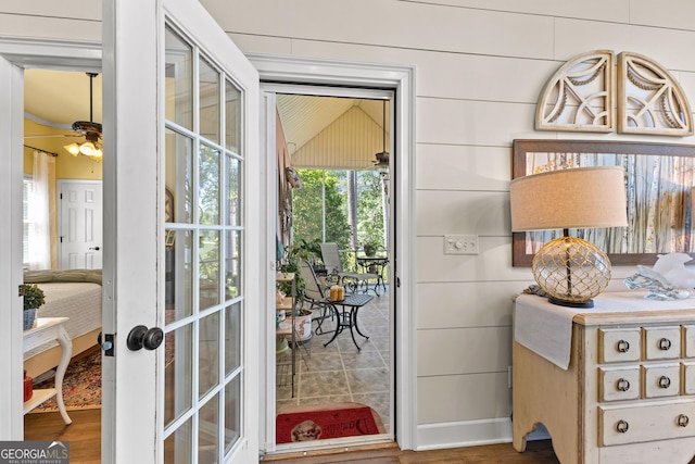 entryway with ceiling fan and wooden walls