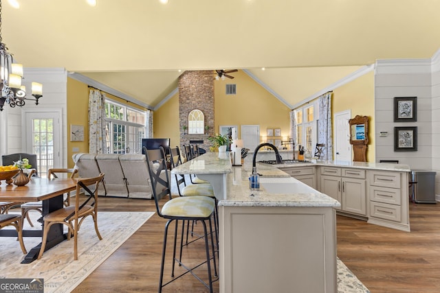 kitchen featuring a breakfast bar area, dark hardwood / wood-style flooring, pendant lighting, and a center island with sink