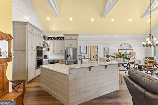 kitchen with decorative light fixtures, a spacious island, a breakfast bar area, stainless steel appliances, and light stone counters