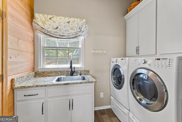 clothes washing area with washing machine and dryer, cabinets, wood walls, and sink