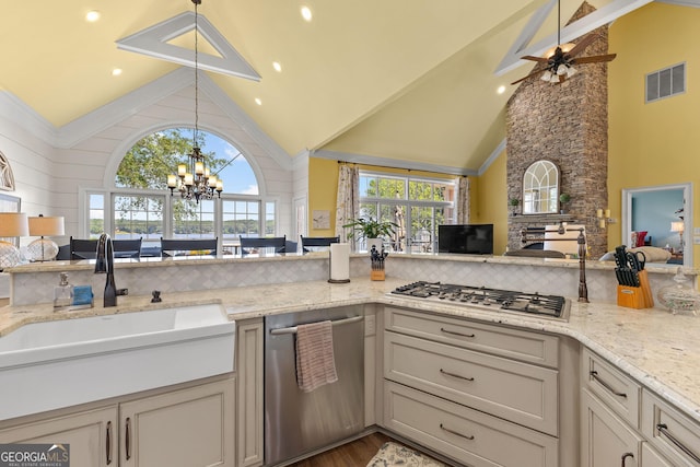 kitchen with high vaulted ceiling, sink, light stone counters, and stainless steel appliances