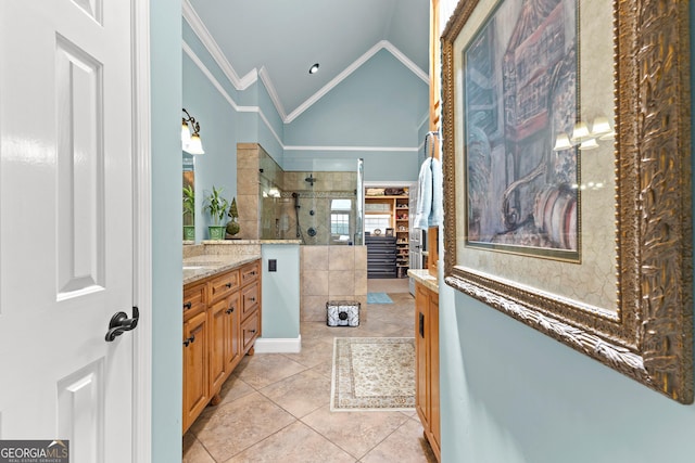 bathroom featuring tiled shower, tile patterned flooring, vaulted ceiling, ornamental molding, and vanity