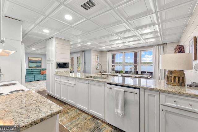 kitchen featuring white cabinets, stainless steel appliances, sink, a water view, and light stone counters