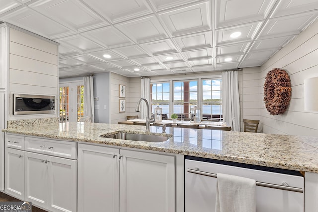 kitchen with a water view, sink, light stone counters, and white cabinetry