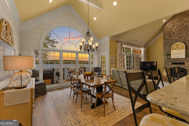 dining area featuring high vaulted ceiling, a fireplace, an inviting chandelier, and hardwood / wood-style flooring