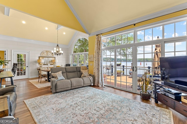 living room with a notable chandelier, ornamental molding, french doors, and high vaulted ceiling