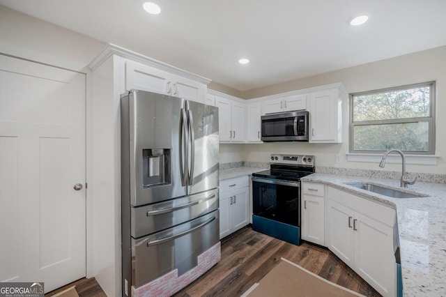 kitchen with light stone countertops, stainless steel appliances, dark wood-type flooring, sink, and white cabinets