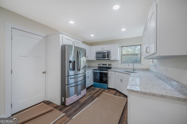 kitchen featuring light stone countertops, dark hardwood / wood-style flooring, stainless steel appliances, sink, and white cabinetry