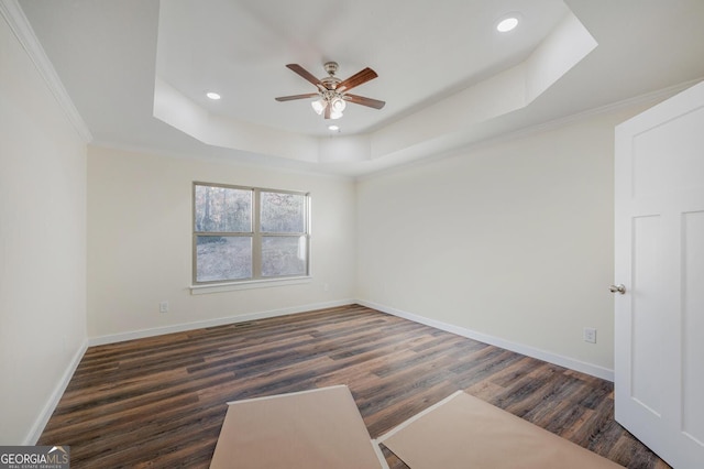 empty room with dark hardwood / wood-style flooring, ceiling fan, and a raised ceiling