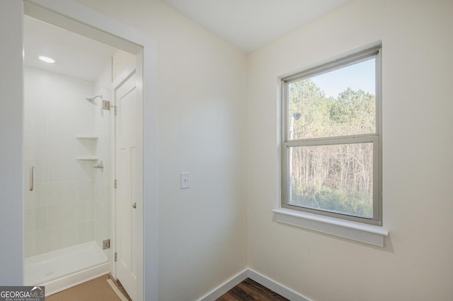 bathroom with a tile shower, hardwood / wood-style floors, and a healthy amount of sunlight