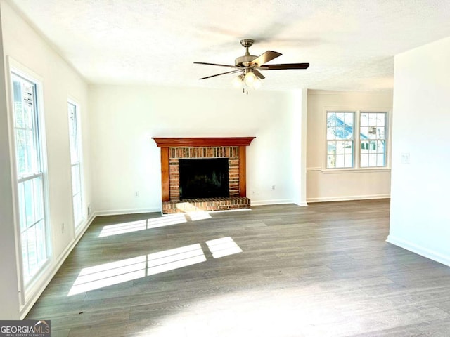 unfurnished living room with dark hardwood / wood-style floors, ceiling fan, a textured ceiling, and a brick fireplace