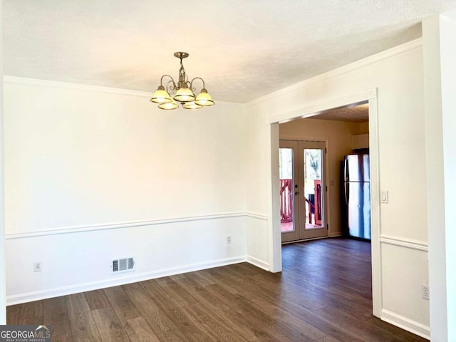 spare room featuring french doors, a textured ceiling, dark hardwood / wood-style flooring, and a notable chandelier