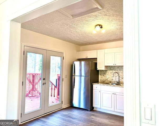 kitchen featuring stainless steel fridge, french doors, a textured ceiling, sink, and white cabinets