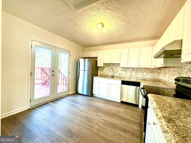 kitchen with appliances with stainless steel finishes, french doors, extractor fan, sink, and white cabinetry