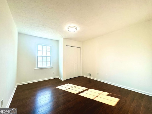 unfurnished bedroom with a closet, dark hardwood / wood-style flooring, and a textured ceiling