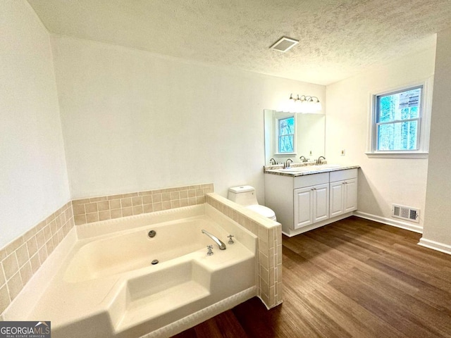 bathroom with a bathtub, vanity, toilet, a textured ceiling, and wood-type flooring