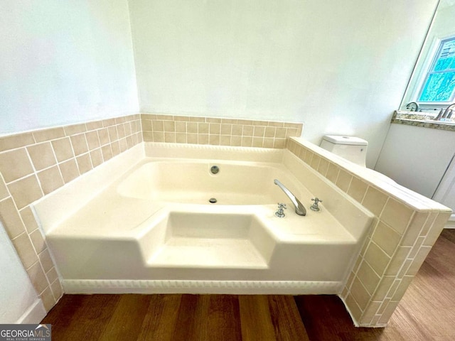 bathroom featuring a washtub, hardwood / wood-style floors, and toilet