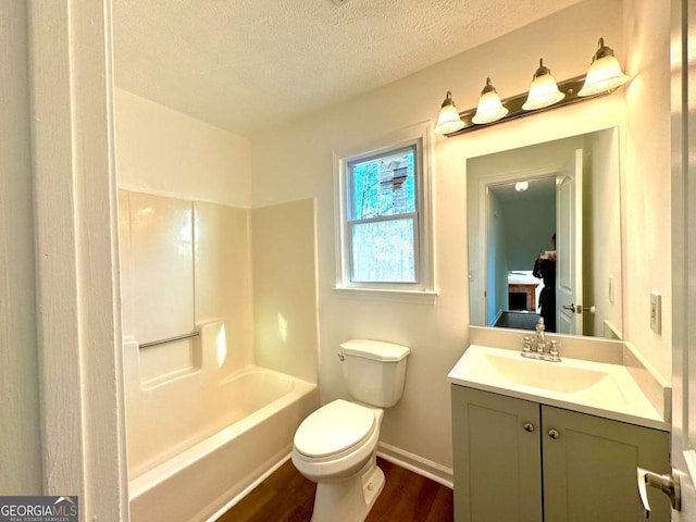 full bathroom featuring washtub / shower combination, hardwood / wood-style floors, a textured ceiling, toilet, and vanity