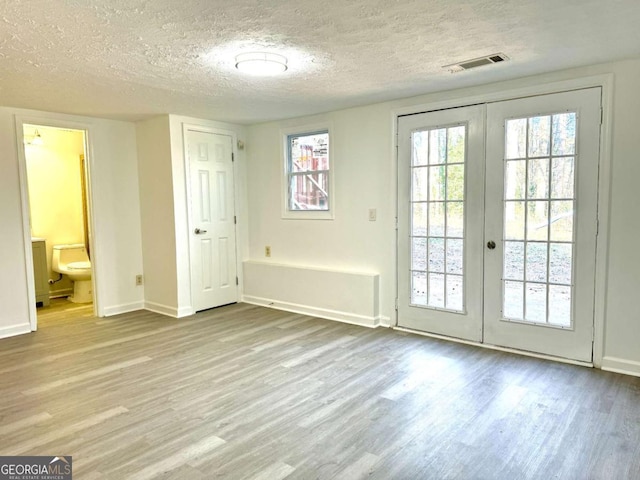 entryway featuring french doors, a textured ceiling, and light hardwood / wood-style flooring