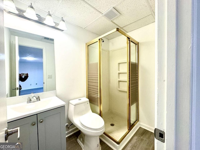 bathroom with a paneled ceiling, vanity, toilet, walk in shower, and wood-type flooring