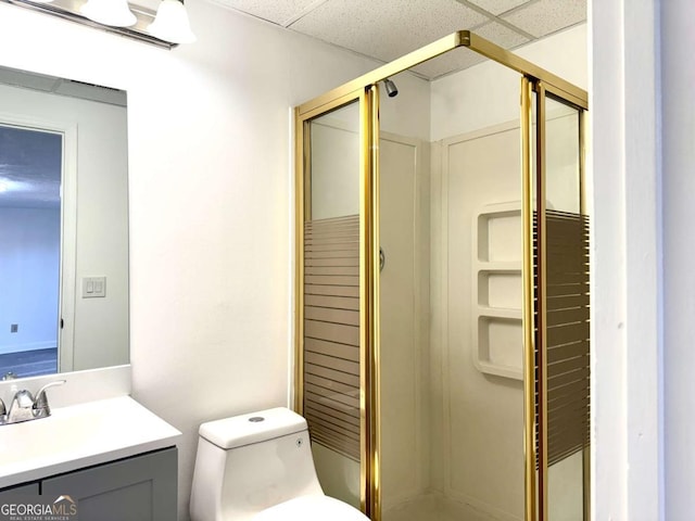 bathroom featuring a paneled ceiling, vanity, toilet, and a shower with door