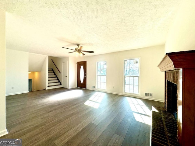 unfurnished living room with a fireplace, a textured ceiling, dark hardwood / wood-style floors, and ceiling fan