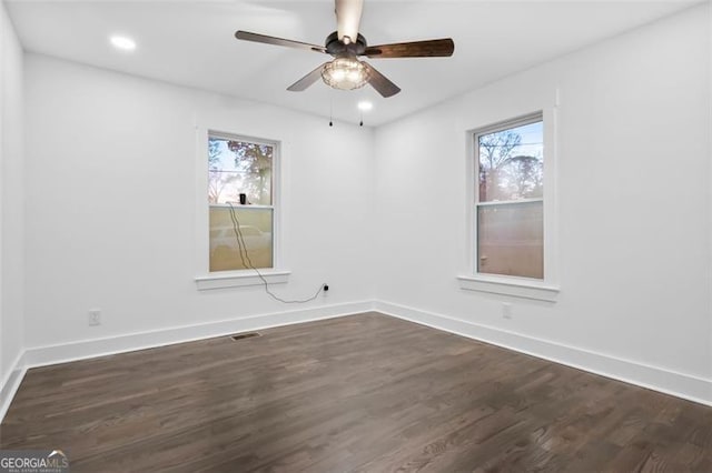 spare room with a wealth of natural light, ceiling fan, and dark wood-type flooring