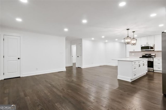 kitchen with appliances with stainless steel finishes, a center island, decorative light fixtures, and white cabinetry