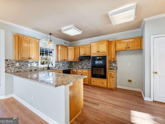 kitchen with hanging light fixtures, light stone counters, backsplash, kitchen peninsula, and black appliances